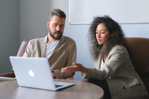 Frau und Mann sitzen gemeinsam an einem Tisch vor einem Laptop